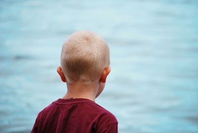 Rear view of boy standing against sea