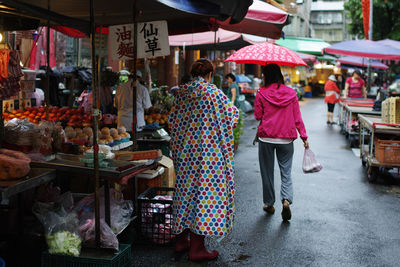 Rear view of people walking at market stall in city