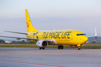 Yellow airplane on airport runway against sky