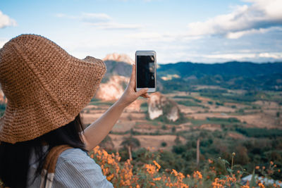 Rear view of woman photographing camera on mobile phone