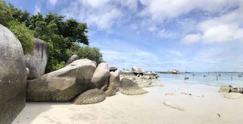 Statue by rock formation against sky