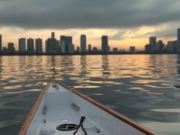 Scenic view of river by buildings against sky during sunset