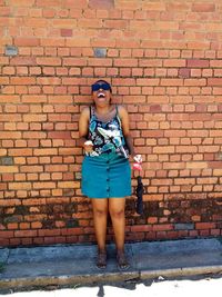 Portrait of woman standing against brick wall