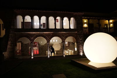 Rear view of people walking in illuminated building