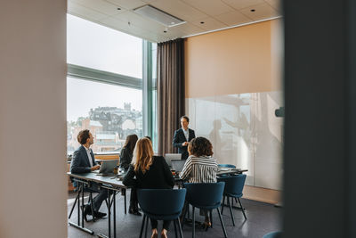 Male entrepreneur taking team meeting with colleagues in board room at office