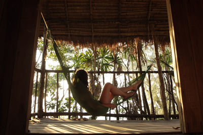 Side view of woman sitting on hammock