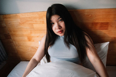 Portrait of woman sitting on bed at home