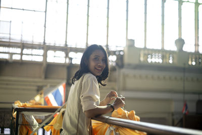 Portrait of smiling young woman standing against built structure