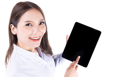 Portrait of smiling woman holding smart phone against white background