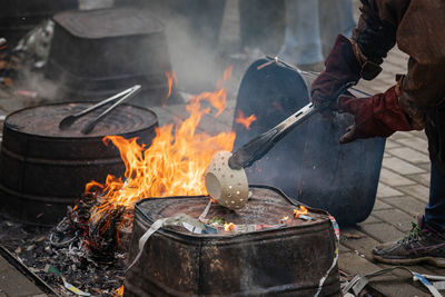 Baked ceramic bowl held by tongs with protective gloves being loaded into a reduction fire