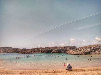 People at beach against sky