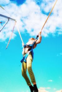 Low angle view of man holding rope against blue sky