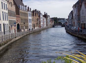 Canal amidst buildings in city against sky