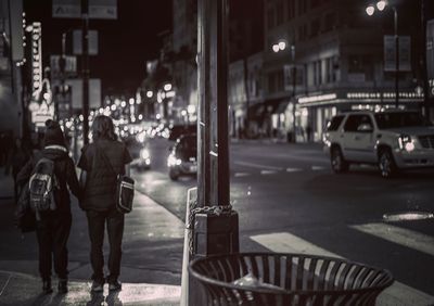 People walking on sidewalk in city at night