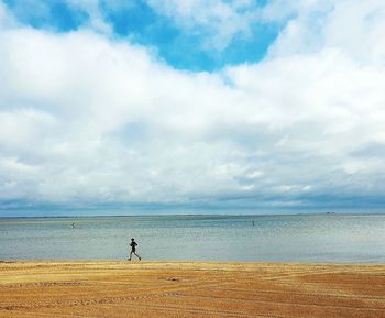 Man running on beach against sky