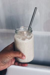 Cropped hand holding drink against wall