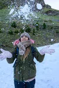 Portrait of young woman with arms outstretched standing on snow covered field