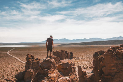 Man standing on rock against sky