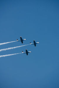 Low angle view of airplane flying against clear blue sky