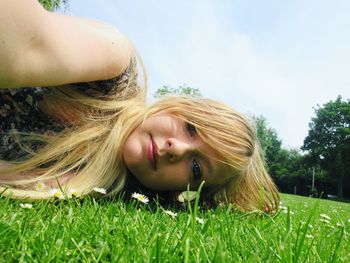 Portrait of woman lying on grassy field