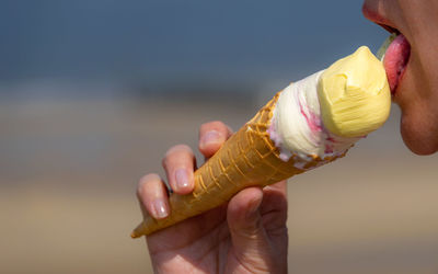 Cropped image of woman licking ice cream outdoors