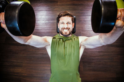 Portrait of young woman with arms raised standing on hardwood floor