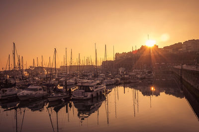 Boats moored in sea at sunset