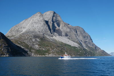 Scenic view of sea and mountains against clear blue sky