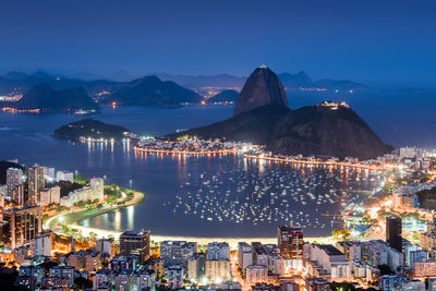 Illuminated cityscape and sugarloaf mountain by guanabara bay