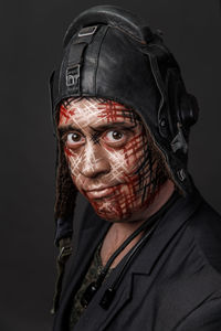 Portrait of man with face paint wearing headwear against gray background