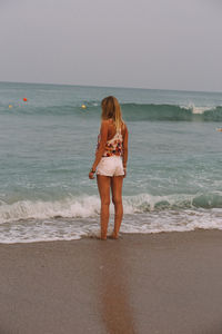 Full length of young woman standing on beach