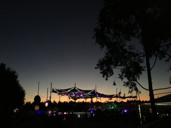 Silhouette people in amusement park against sky at night