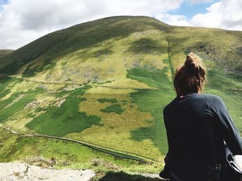 Rear view of woman standing on landscape against sky