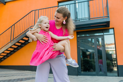 Portrait of young woman standing against building