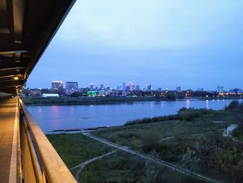 Illuminated buildings by river against sky in city