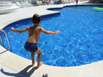 Full length of shirtless boy jumping in swimming pool