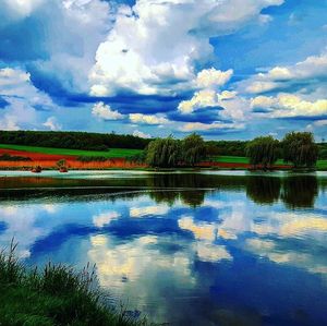 Scenic view of calm lake against cloudy sky