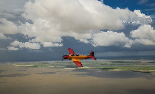 Airplane flying over sea against sky