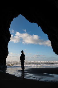 Silhouette man standing on beach against sky