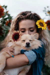 Midsection of woman holding dog at flower