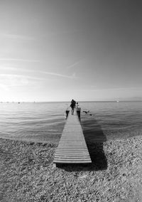 People walking on pier over sea against sky