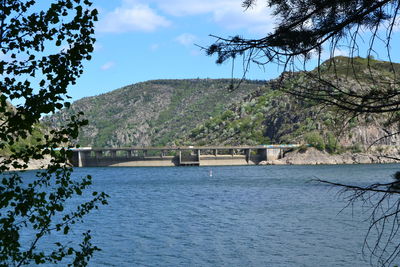 Scenic view of river by mountains against sky