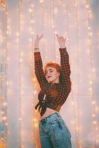 Happy woman standing against illuminated lighting equipment