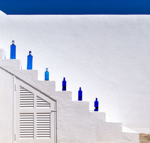 Blue bottles on staircase against white wall