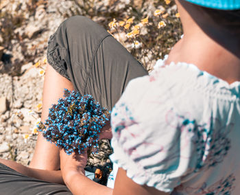 High angle view of woman holding flowers while sitting outdoors