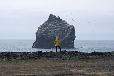 Rear view of woman walking at beach against sky