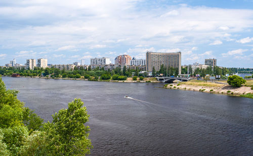 Scenic view of river by city buildings against sky