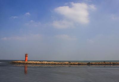 Lighthouse by sea against sky