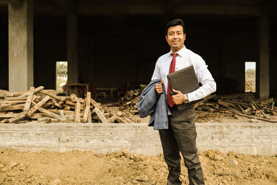 Portrait of young man standing at construction site