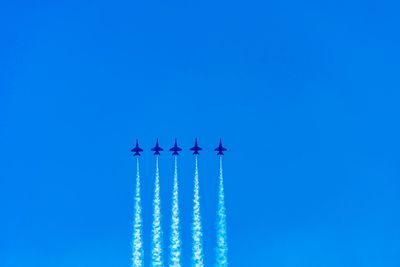 Low angle view of airshow against clear blue sky